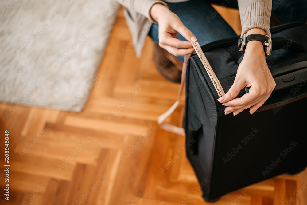 Close-up of woman hands measuring luggage before going on a trip.