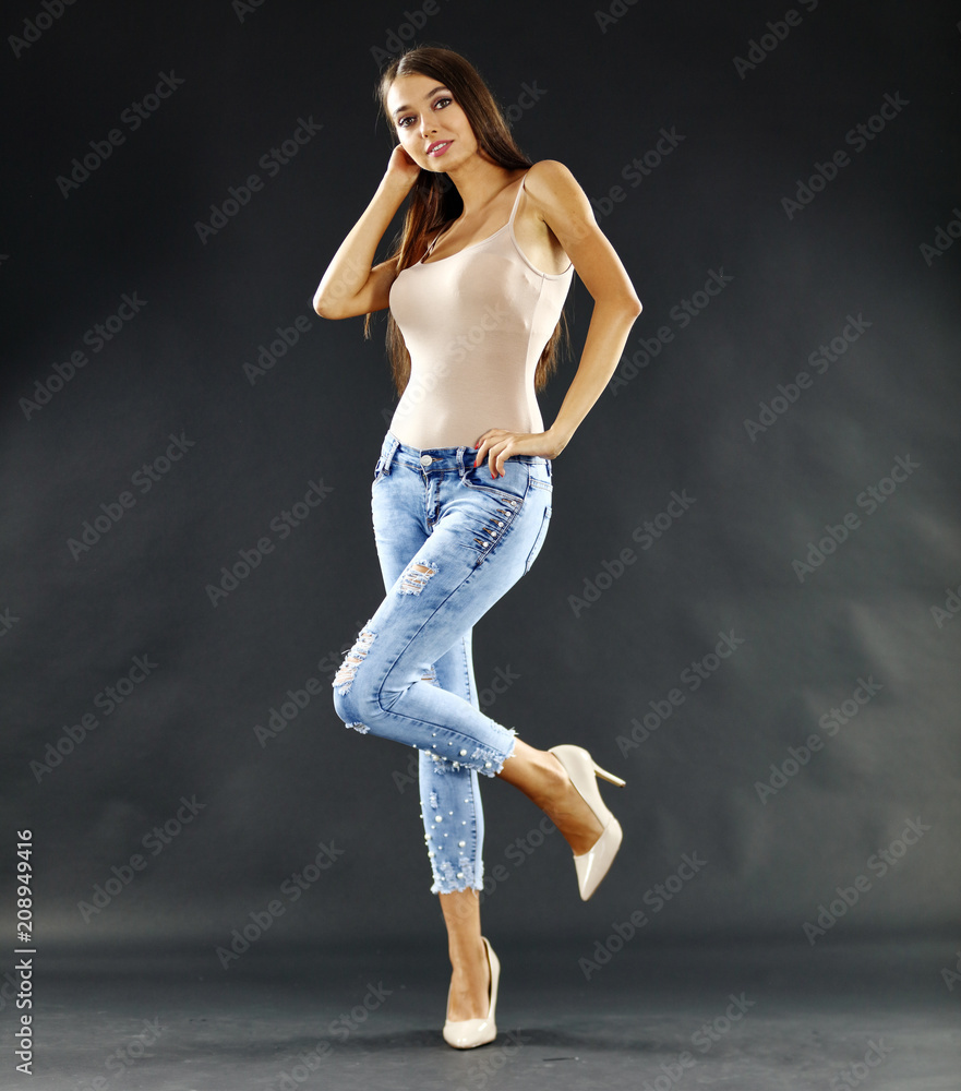 slim young woman in jeans and mood dark background. 
