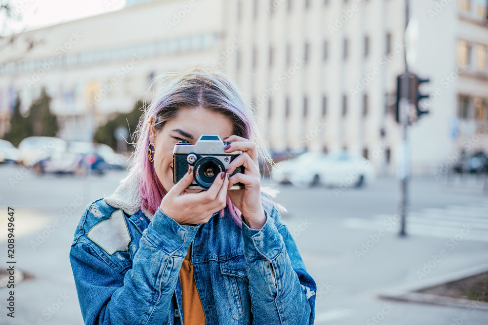 Girl in denim jacket taking a photo with camera.