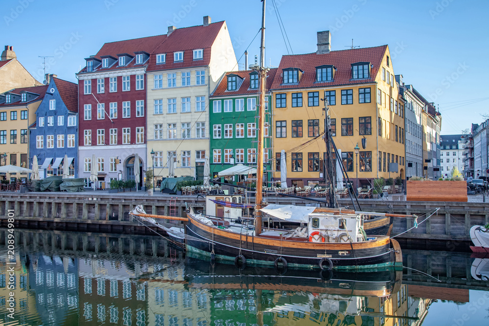 COPENHAGEN, DENMARK - MAY 6, 2018: boat and beautiful colorful buildings reflected in calm water of harbor, copenhagen, denmark