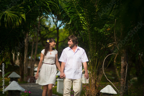happy bride and groom walking in the rainforest, holding hands