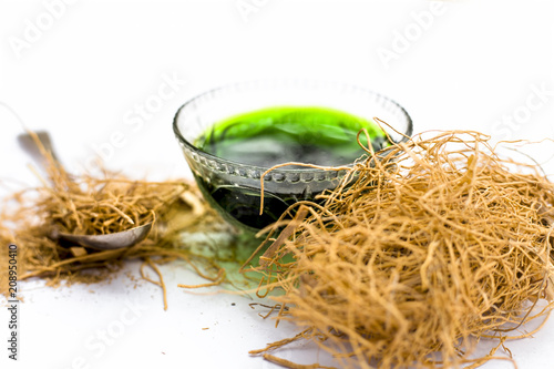 Close up of dark green colored herbal syrup of Khus or vetiver grass isolated on white in a transparent glass used to in various flavored beverages. photo