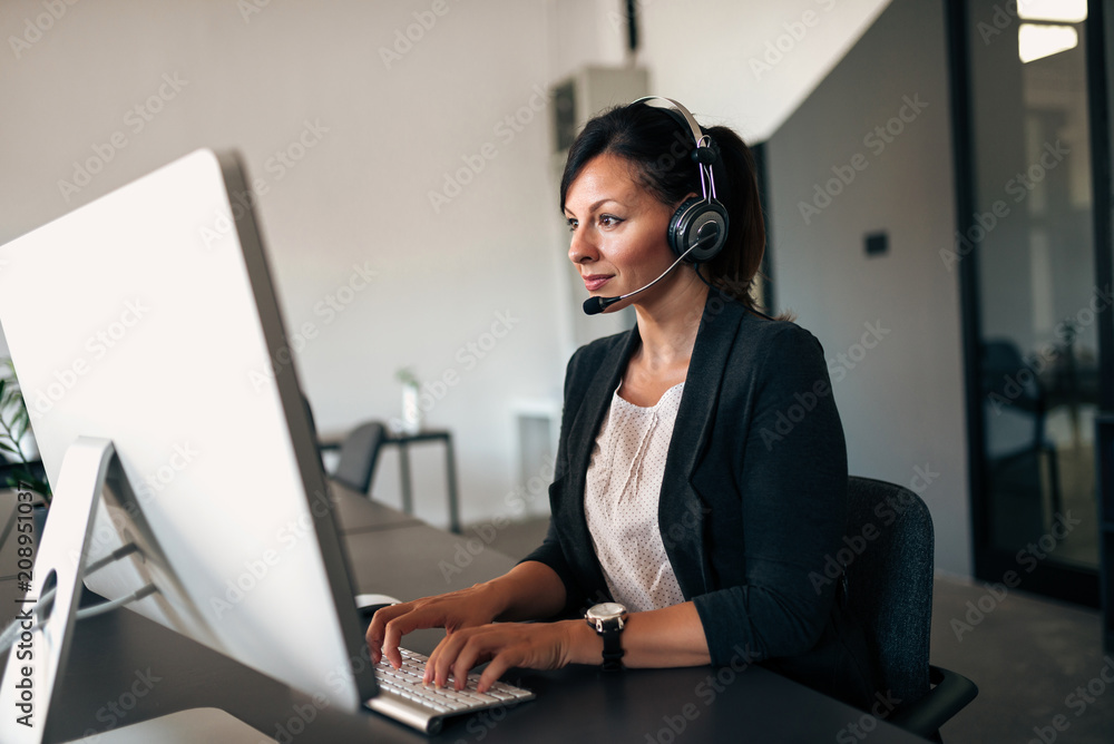 Businesswoman working with headset on computer. Businesswoman working with headset on computer.