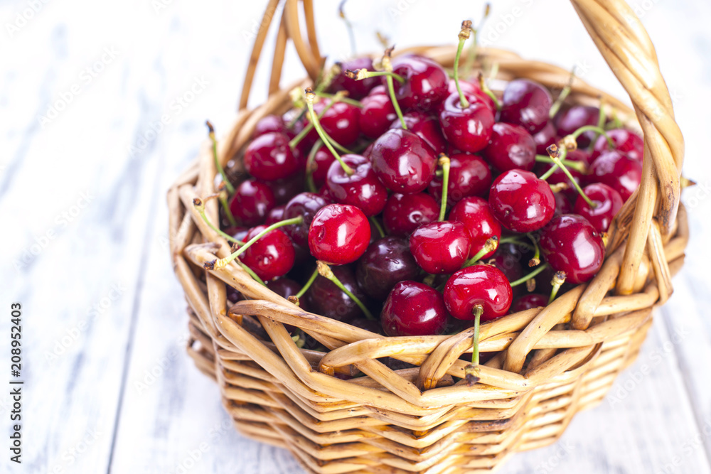A large basket of ripe cherries. Delicious and sweet berries. White wooden background, free space for text. Copy space. A large basket of ripe cherries. Delicious and sweet berries. White wooden background, free space for text. Copy space.