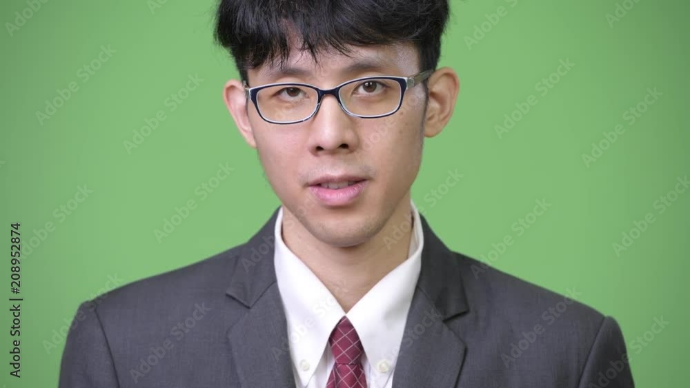 Young Asian businessman against green background Young Asian businessman against green background