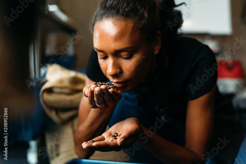 Fotografi Woman examining and smelling the aroma of coffee beans after roasting