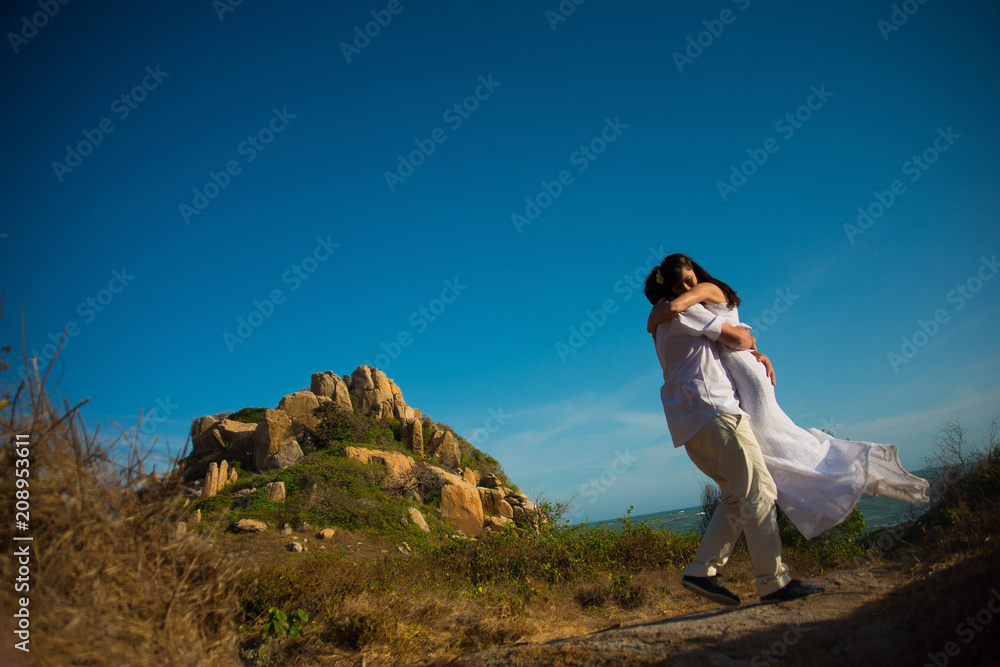 The groom circles the bride in his arms against the mountains and sky