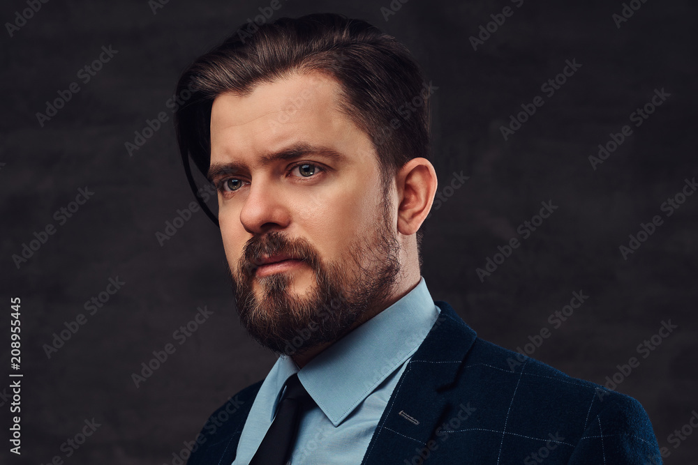 Close-up portrait of a handsome middle-aged man with beard and hairstyle dressed in an elegant formal suit. Isolated on a textured dark background in studio. Close-up portrait of a handsome middle-aged man with beard and hairstyle dressed in an elegant formal suit. Isolated on a textured dark background in studio.