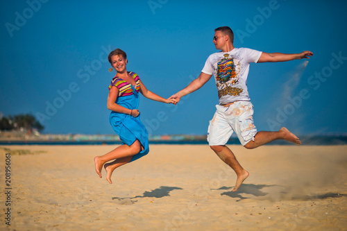 Man and woman have fun jumping on the beach