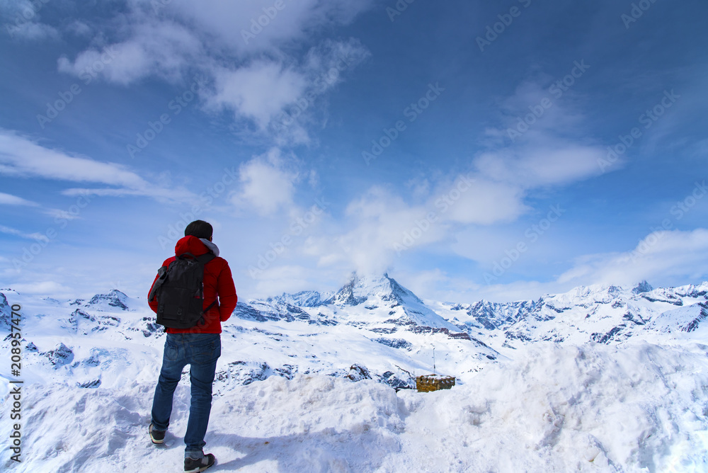Man in red jacket is looking Matterhorn peak on Gornagrat peak, Zermatt, Switzerland