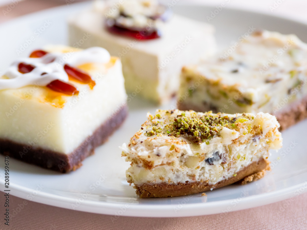 White plate full of different pastries. Tasty desserts with topping, pistachios.