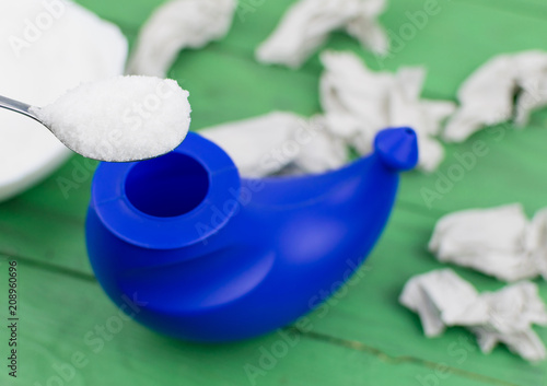 A device for washing the nose and crumpled toilet paper with snot in the background. photo