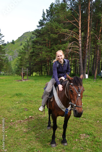 A girl riding a horse in a mountainous area. Travel content.