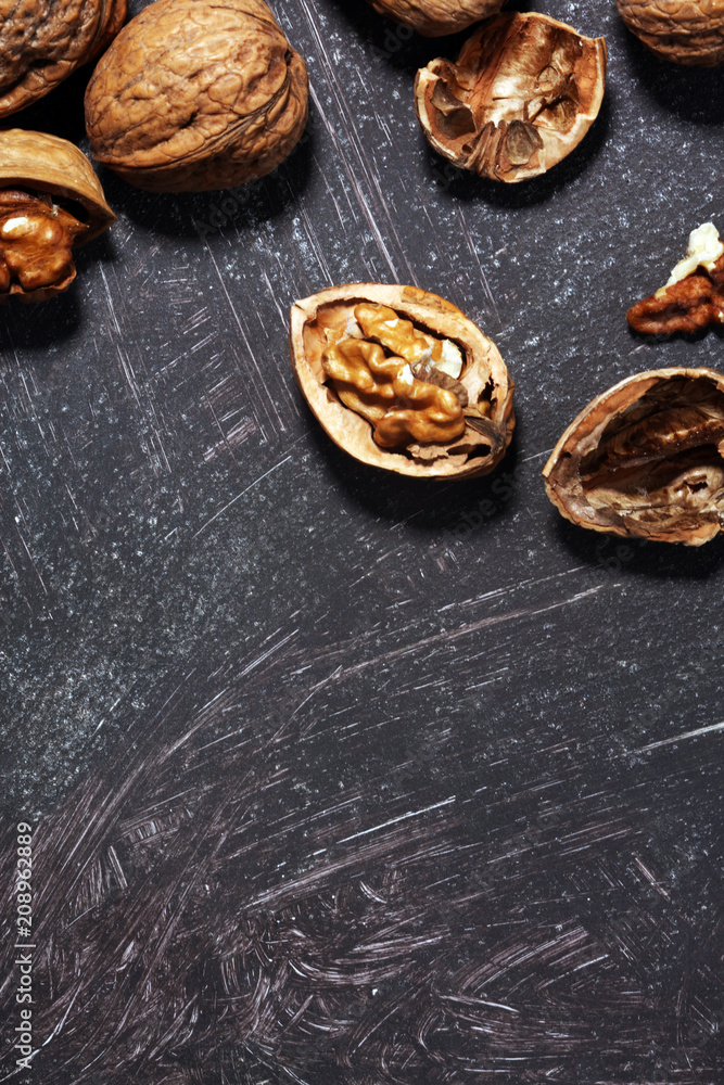 Fototapeta premium Walnut kernels and whole walnuts on rustic old table