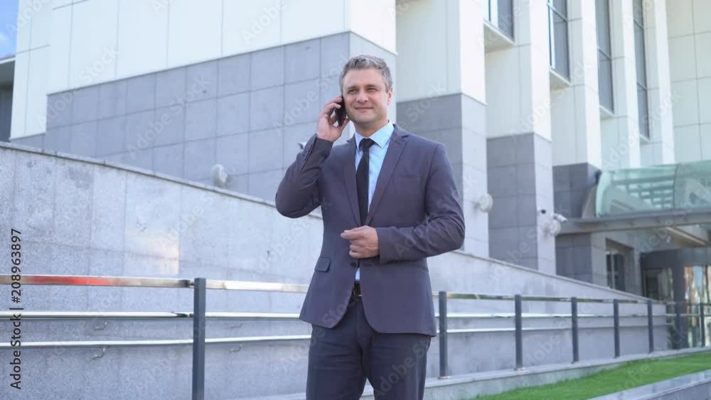 Attractive middle-aged man. Serious businessman Talking on the phone An image of a general plan, against the background of modern office buildings. A solid man in a jacket and tie 4K Attractive middle-aged man. Serious businessman Talking on the phone An image of a general plan, against the background of modern office buildings. A solid man in a jacket and tie 4K