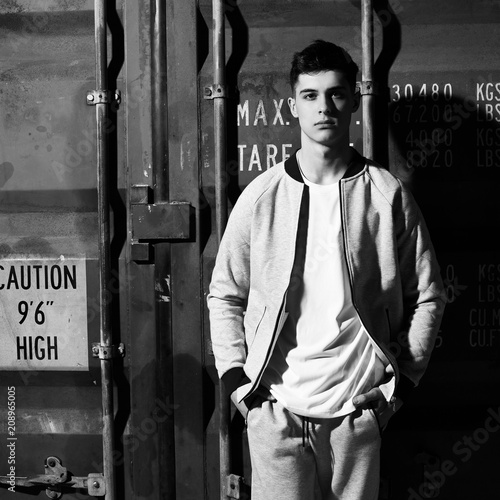 Young handsome sporty man in gary sport clothes posing against red metal doors of intermodal container photo