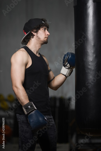 Young boxer posing next to punching bag © Vladimir