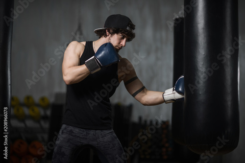 Muscular young boxer training with punching bag © Vladimir