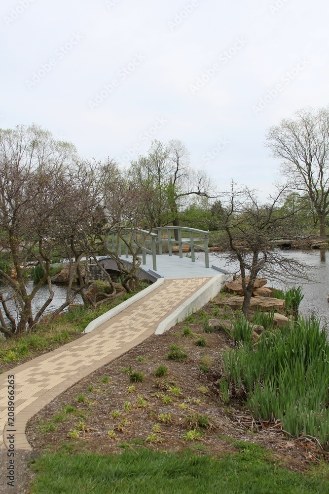 The walkway up to the wood bridge over the pond in park.