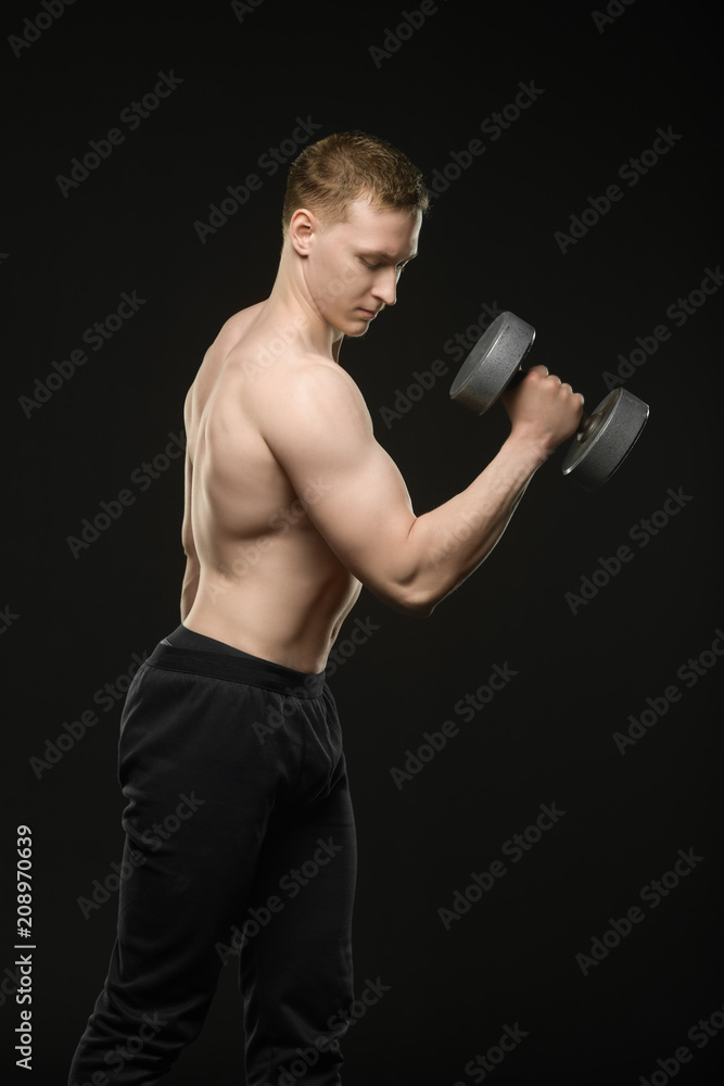 fitness guy trains a bicep standing on a black background