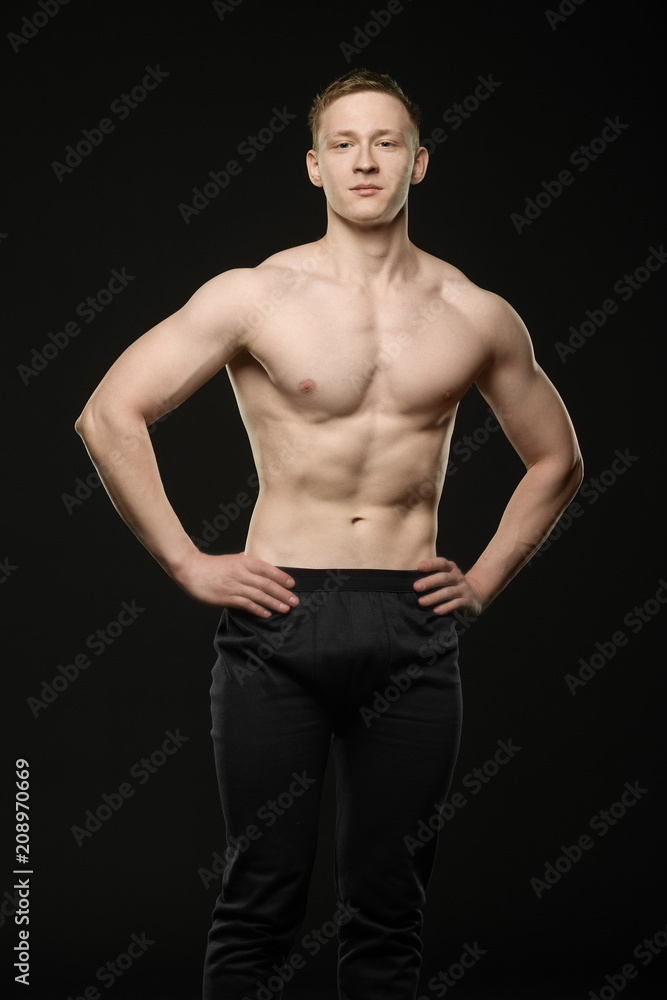 a young bodybuilder shows a muscular body on a black background a young bodybuilder shows a muscular body on a black background