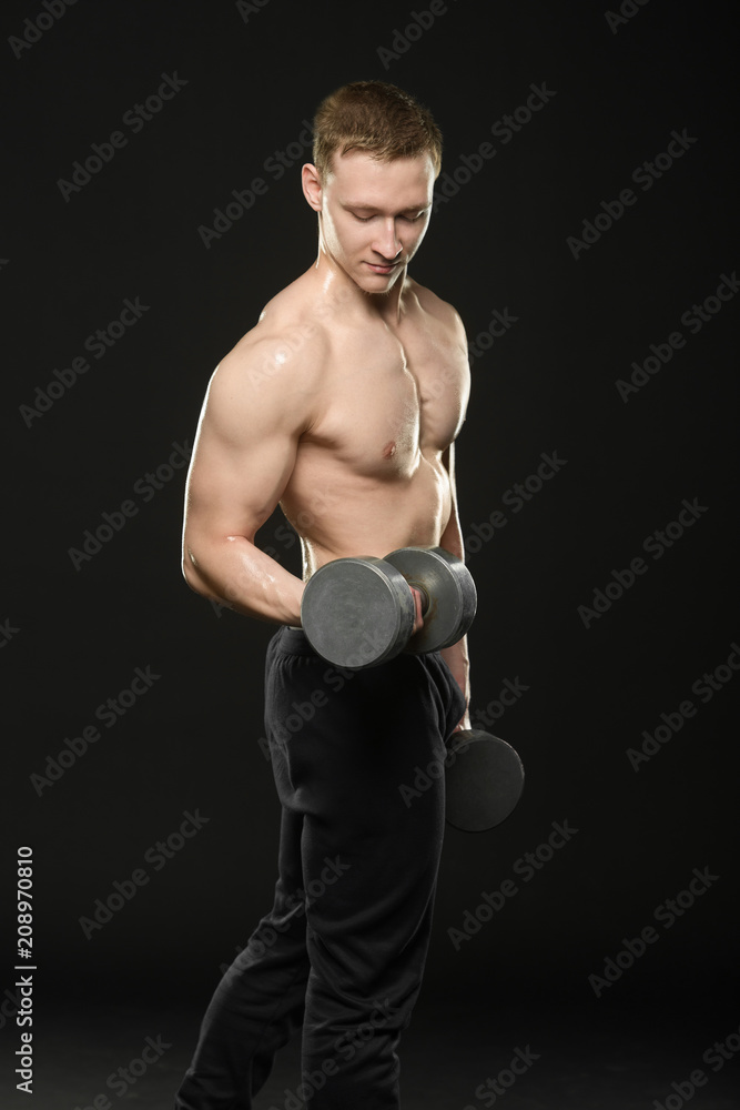 the guy trains with dumbbells on a black background