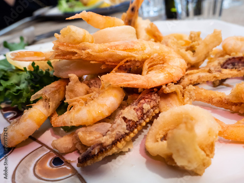 delicious Mediterranean dish of fried fish, sea food, calamari and shrimp with an ornamental lettuce leaf in a delicious dish of an Italian restaurant