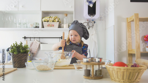 Girl baker mixes the mixture for cookies with a whisk