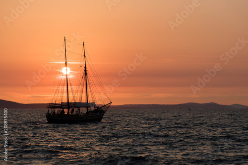 Ship sailing at sunset in Croatia, crossing the sun