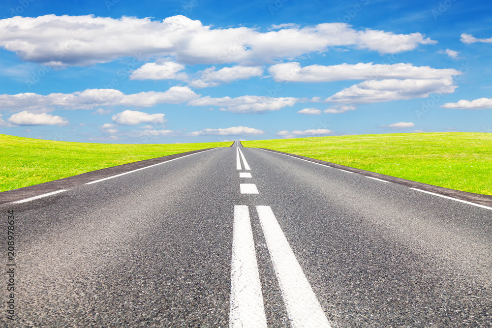 Naklejka premium Asphalt road, meadow and sky. The road is intended for advertising
