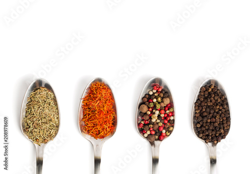 Different spices in iron spoons isolated on white