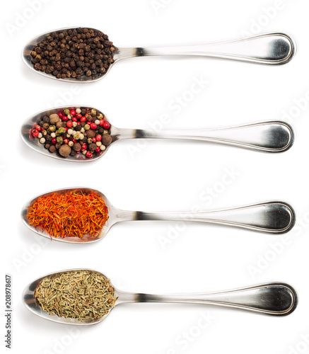 Different spices in iron spoons isolated on white