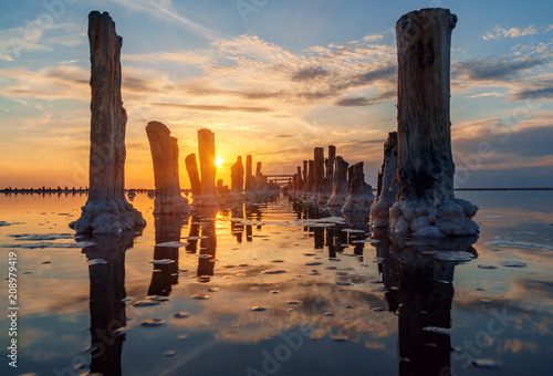 sunset on a pink salt lake, a former mine for the extraction of pink salt. row of wooden pegs overgrown with salt