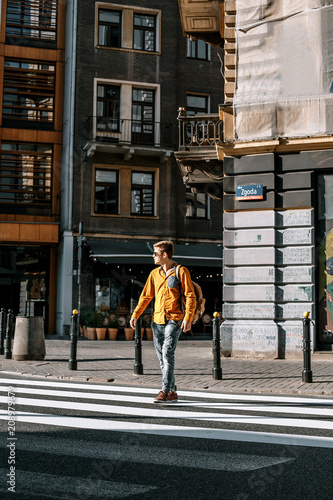 The guy crosses the street through the pedestrian crossing. Stylishly dressed man with a briefcase in a hurry to work and study. The man travels to the cities of .Europe. Poland Warsaw.