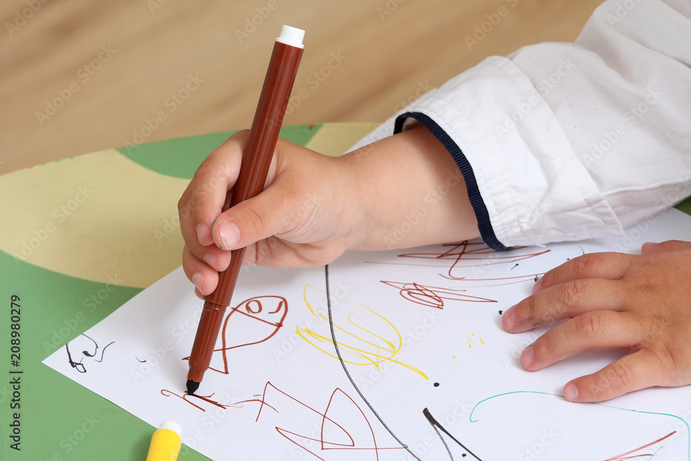 close up on the hand of a child who draws with colored markers close up on the hand of a child who draws with colored markers