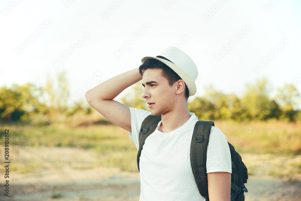 Young man in nature wearing hat and backpack 