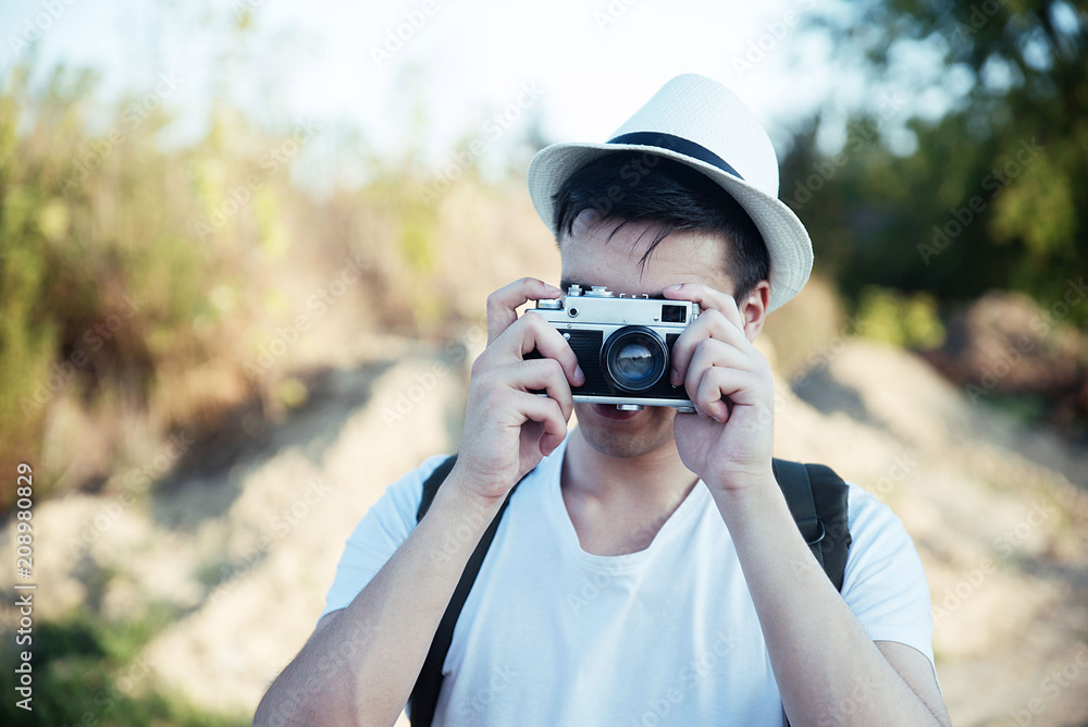 Hipster man taking photos in nature with retro camera