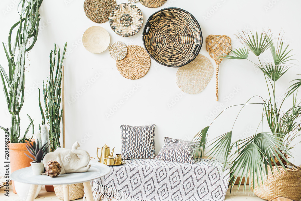 Modern minimal home interior design. Pillows, golden teapot, decorative straw plates, Scandinavian blanket, tropical palm tree, succulent and decorations. - obrazy, fototapety, plakaty 
