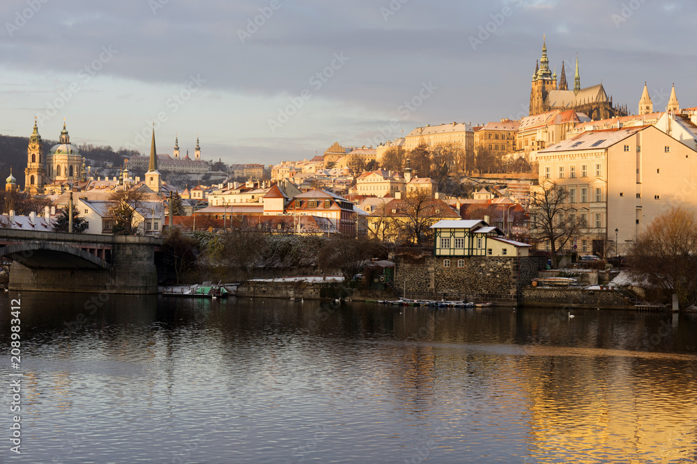 Sunny snowy early morning Prague Lesser Town with gothic Castle above River Vltava, Czech republic