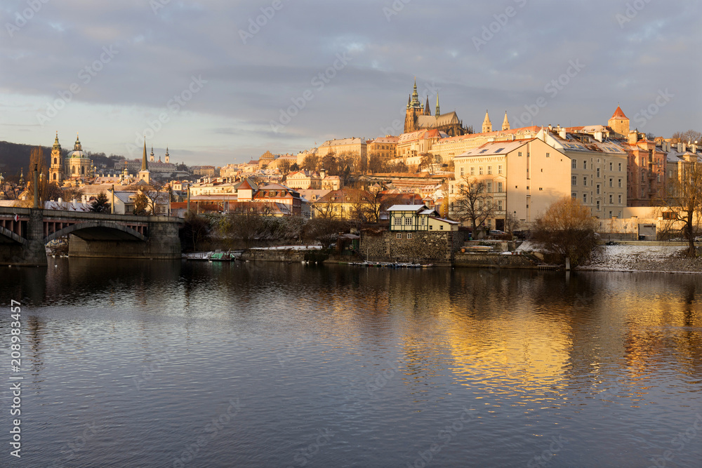 Sunny snowy early morning Prague Lesser Town with gothic Castle above River Vltava, Czech republic