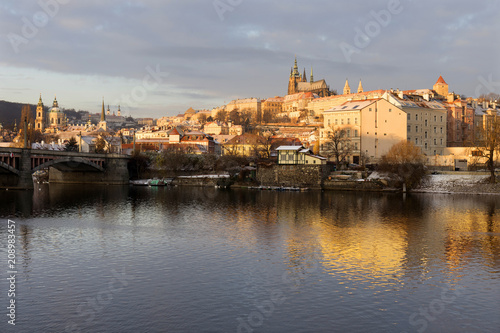 Sunny snowy early morning Prague Lesser Town with gothic Castle above River Vltava, Czech republic