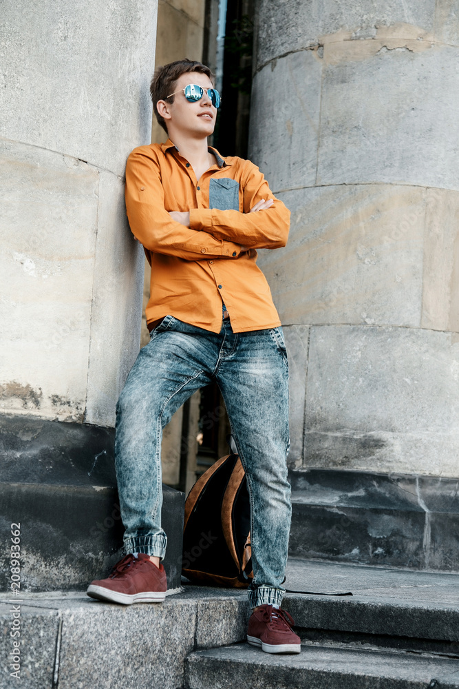 Obraz premium on the streets of Warsaw. The guy in the city center. Travel the European city. Stylishly dressed man with a briefcase in a hurry to work and study. The man travels to the cities of .Europe. Poland