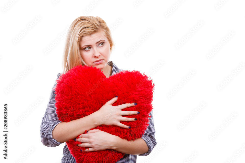 Sad girl holding big red pillow in heart shape Sad girl holding big red pillow in heart shape