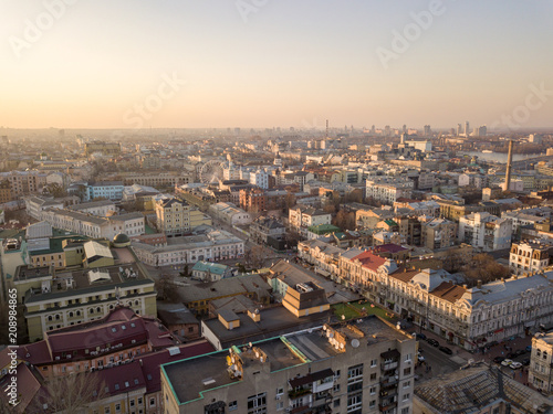 The panoramic bird's eye view from drone to the central historical part of the city Kiev - the Podol district, the Dnieper River in Kiev, Ukraine at summer sunset. © artjazz