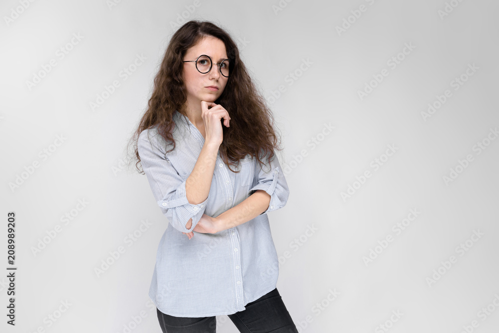 Young brunette girl with glasses. The girl put a finger to her cheek. Young brunette girl with glasses. The girl put a finger to her cheek.
