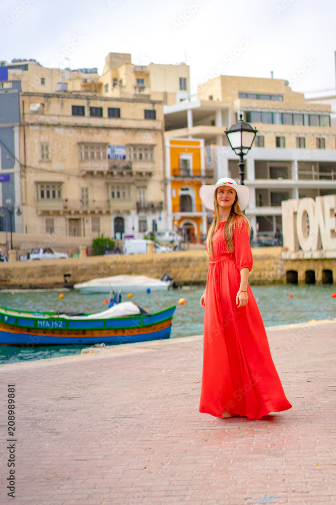 Φωτογραφία Beautiful girl in a red dress walking down the old town by the sea on the island