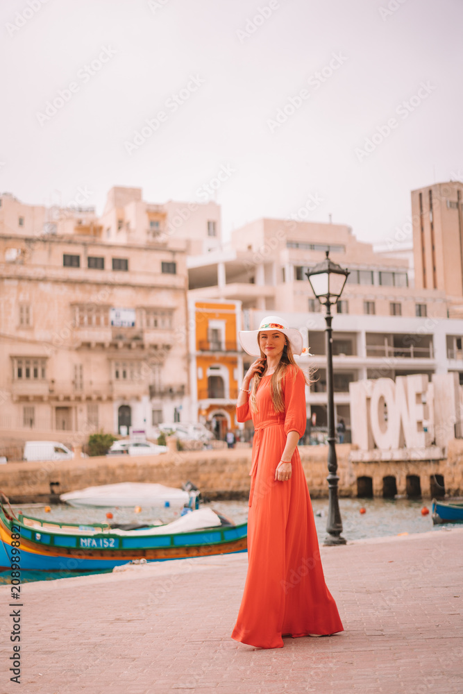 Φωτογραφία Beautiful girl in a red dress walking down the old town by the sea on the island