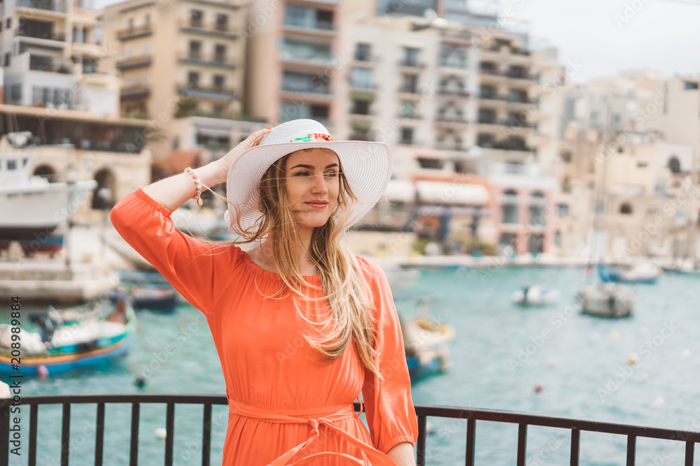 Φωτογραφία Beautiful girl in a red dress walking down the old town by the sea on the island