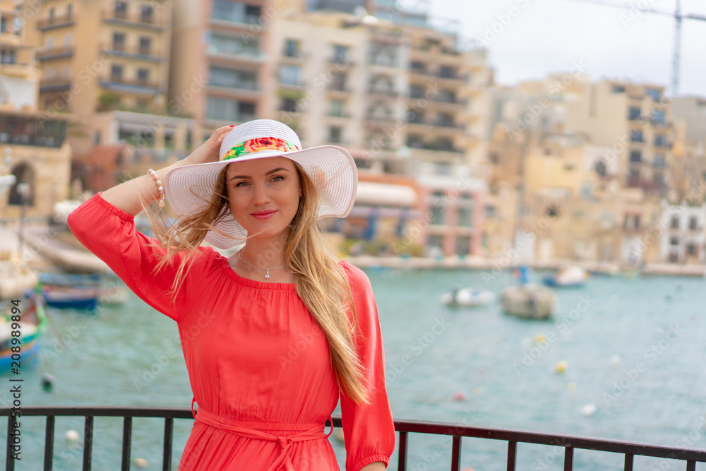 Φωτογραφία Beautiful girl in a red dress walking down the old town by the sea on the island