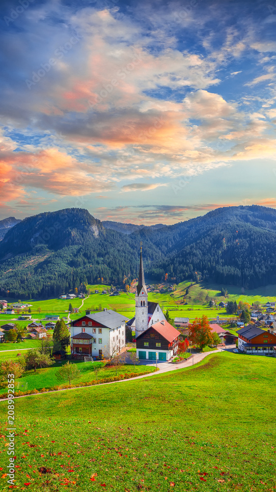 Alpine green fields and traditional wooden houses view of the Gosau village at autumn sunny day.